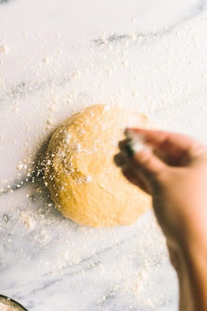 Sprinkling risen dough with flour before rolling